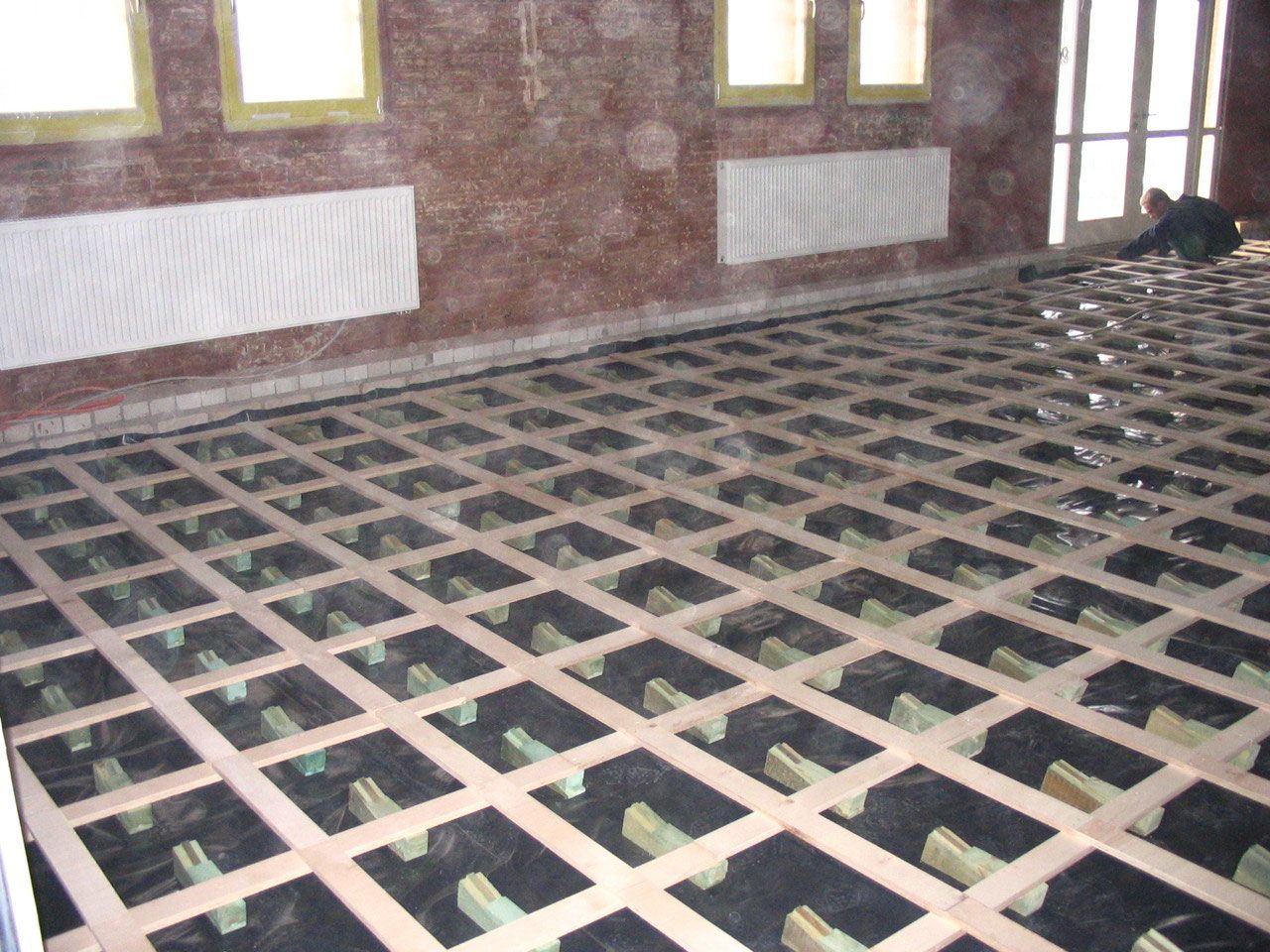 Unterkonstruktion des Schwingbodens vor einer Backsteinwand