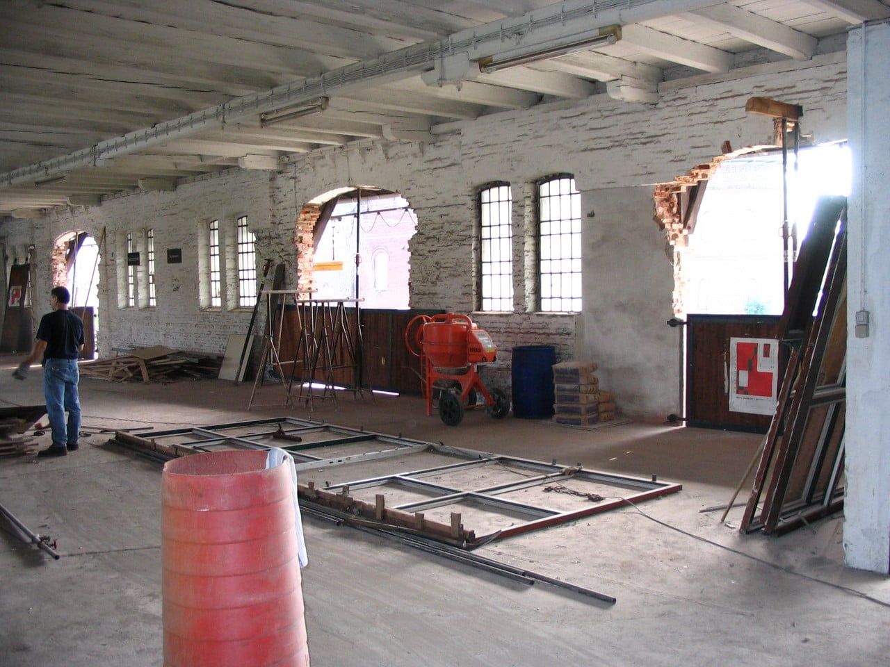 Halle mit am Boden liegenden Stahlrahmen vor Rundbogenfenstern
