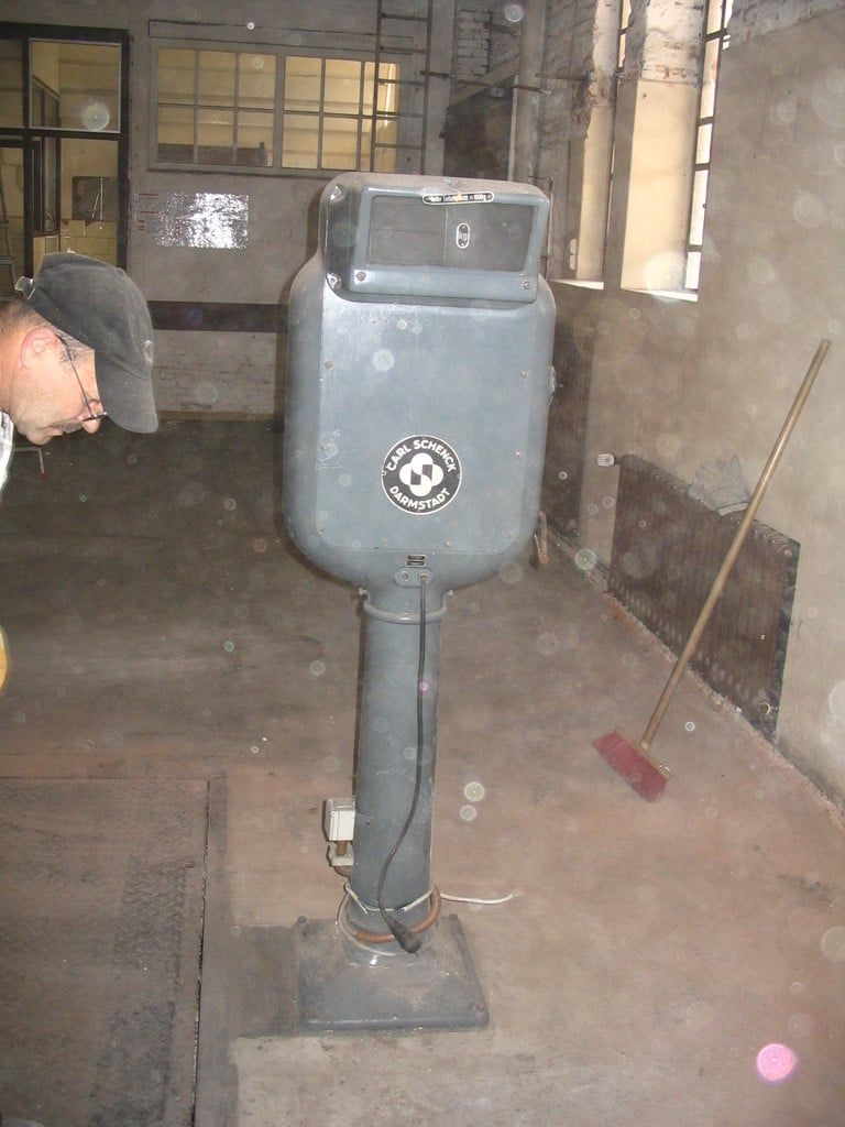 Grauer Standapparat auf einem Sockel in der Halle, daneben ein Helfer
