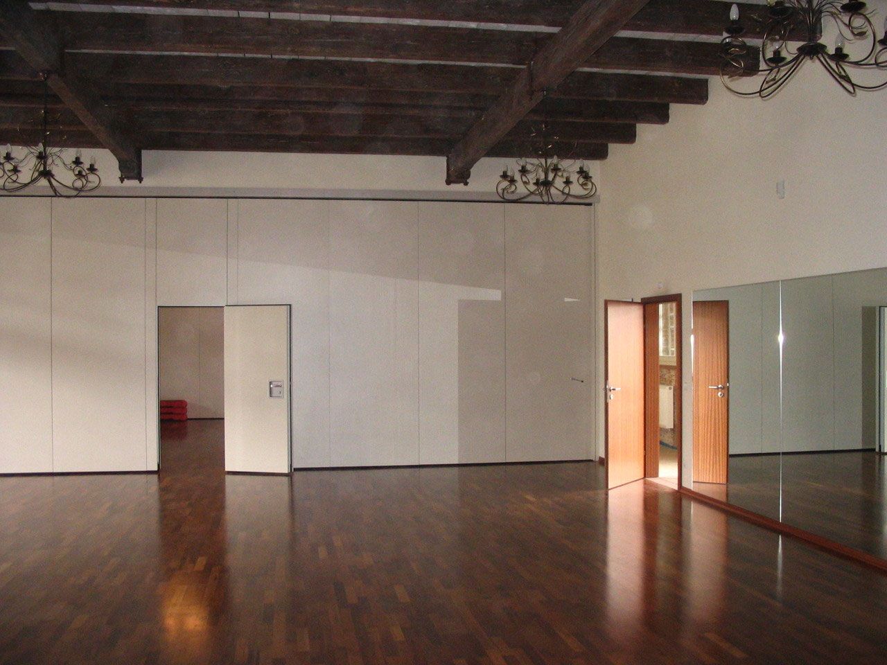 Leerer Tanzsaal mit dunklem Parkett und Holzbalken