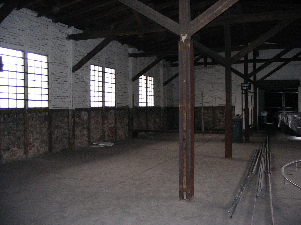Leere Halle mit Holzträgern und weiß gestrichenen Wänden