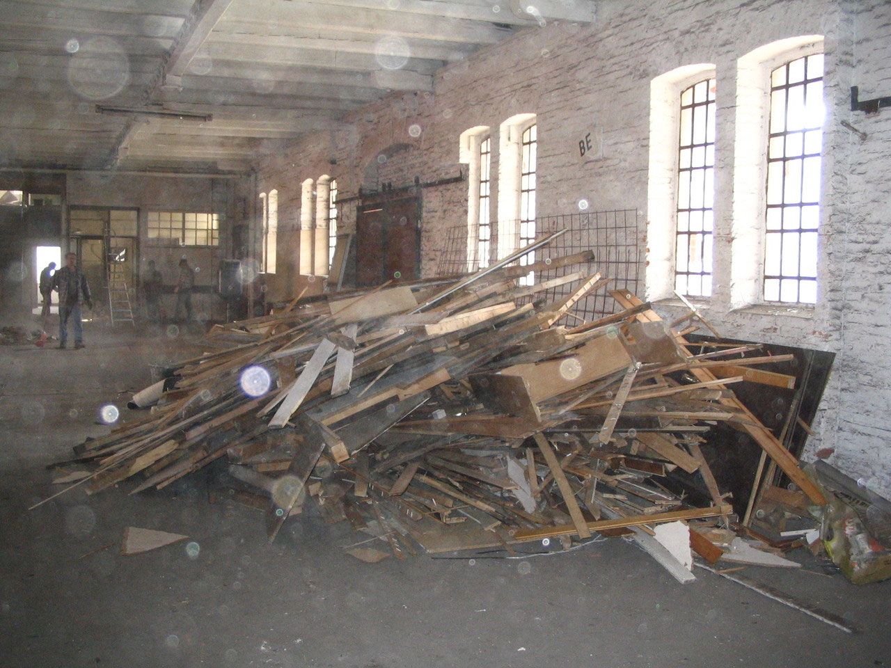 Halle voller Holzschutt vor den hohen Fenstern