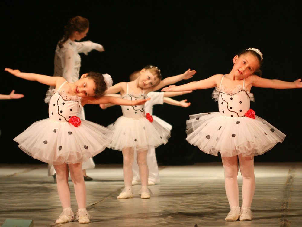 Kindergruppe in weißen Ballettkostümen mit schwarzen Punkten auf der Bühne