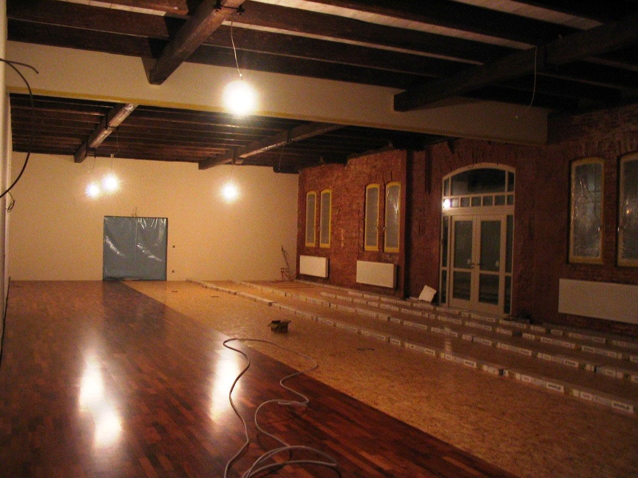 Tanzsaal mit glänzendem Parkett, Backsteinwand und Holzdecke