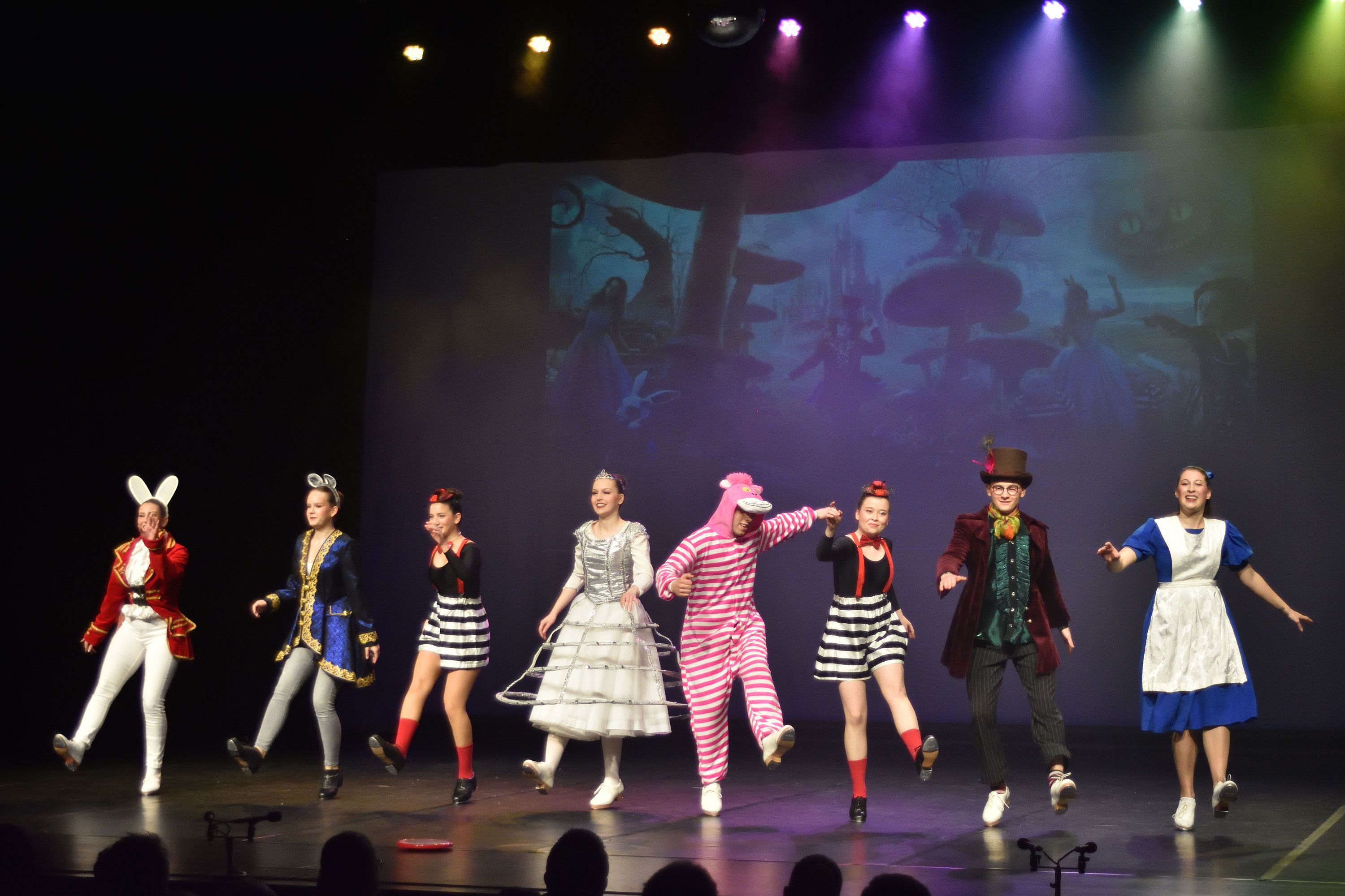 Gruppe in Kostümen aus „Alice im Wunderland“ auf der Bühne