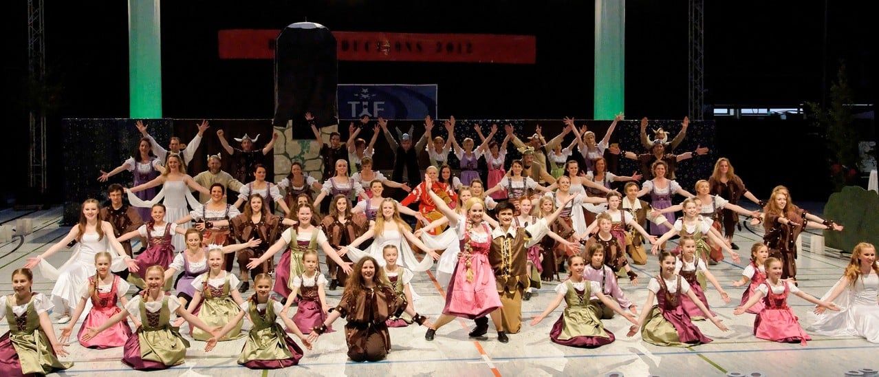 Gruppenbild der Produktion „Rapunzel“ 2012 mit vielen Tänzerinnen und Tänzern in Dirndl- und Märchenkostümen