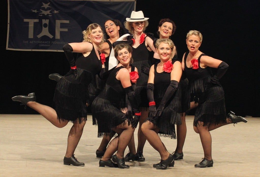 Formation in schwarzen Fransenkleidern mit roten Blumen und weißen Hüten bei einem Turnier 2011