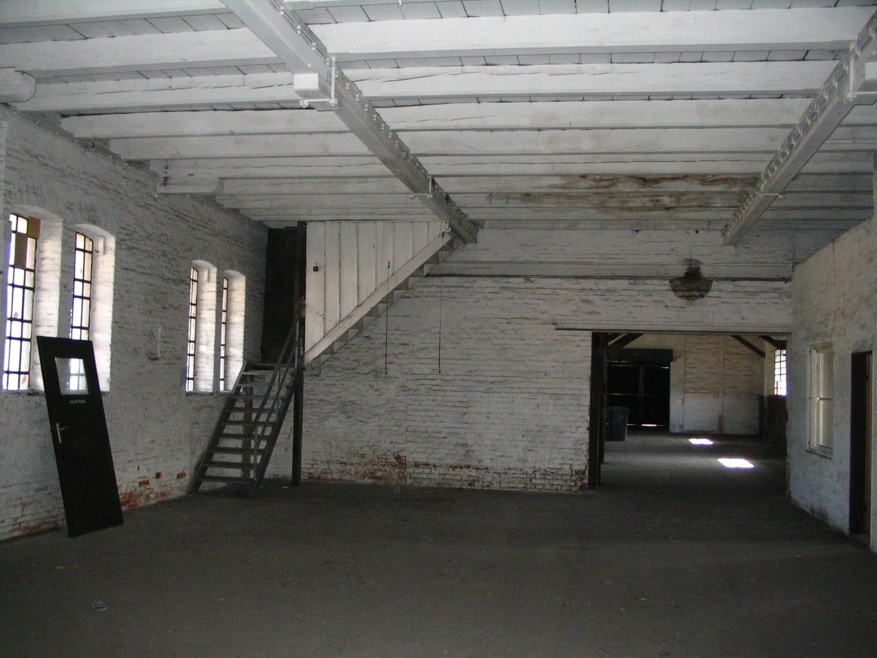 Leere weiße Halle mit Stahltreppe und offenen Durchgängen
